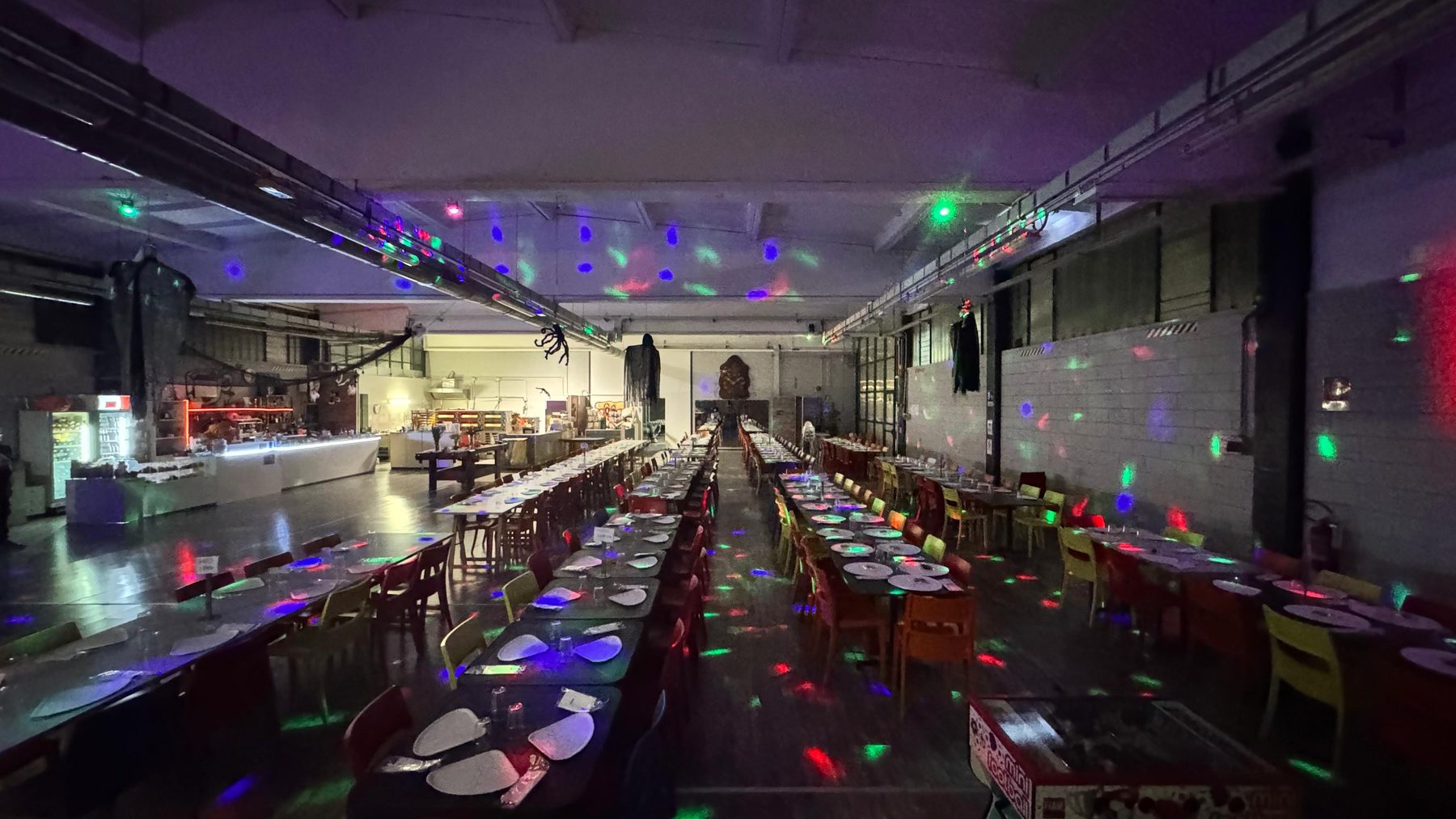 La sala del giropizza di Pito Pitù a Cabiate la sera, con luci colorate e lunghe tavolate apparecchiate